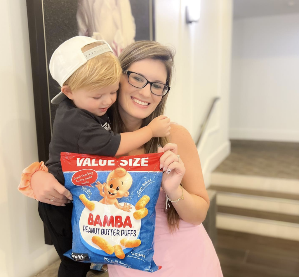 Mom influencer holding a gifted family snack with her toddler at home, showing how Gen Z moms rely on real-life experience and trust when evaluating products.